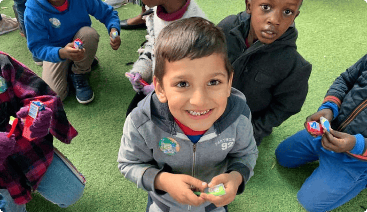 Smiling young boy with healthy teeth, diverse children at a dental health event.