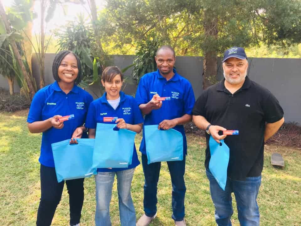 Bright smiling team holding toothbrushes outside dental clinic, promoting oral hygiene and dental care services.